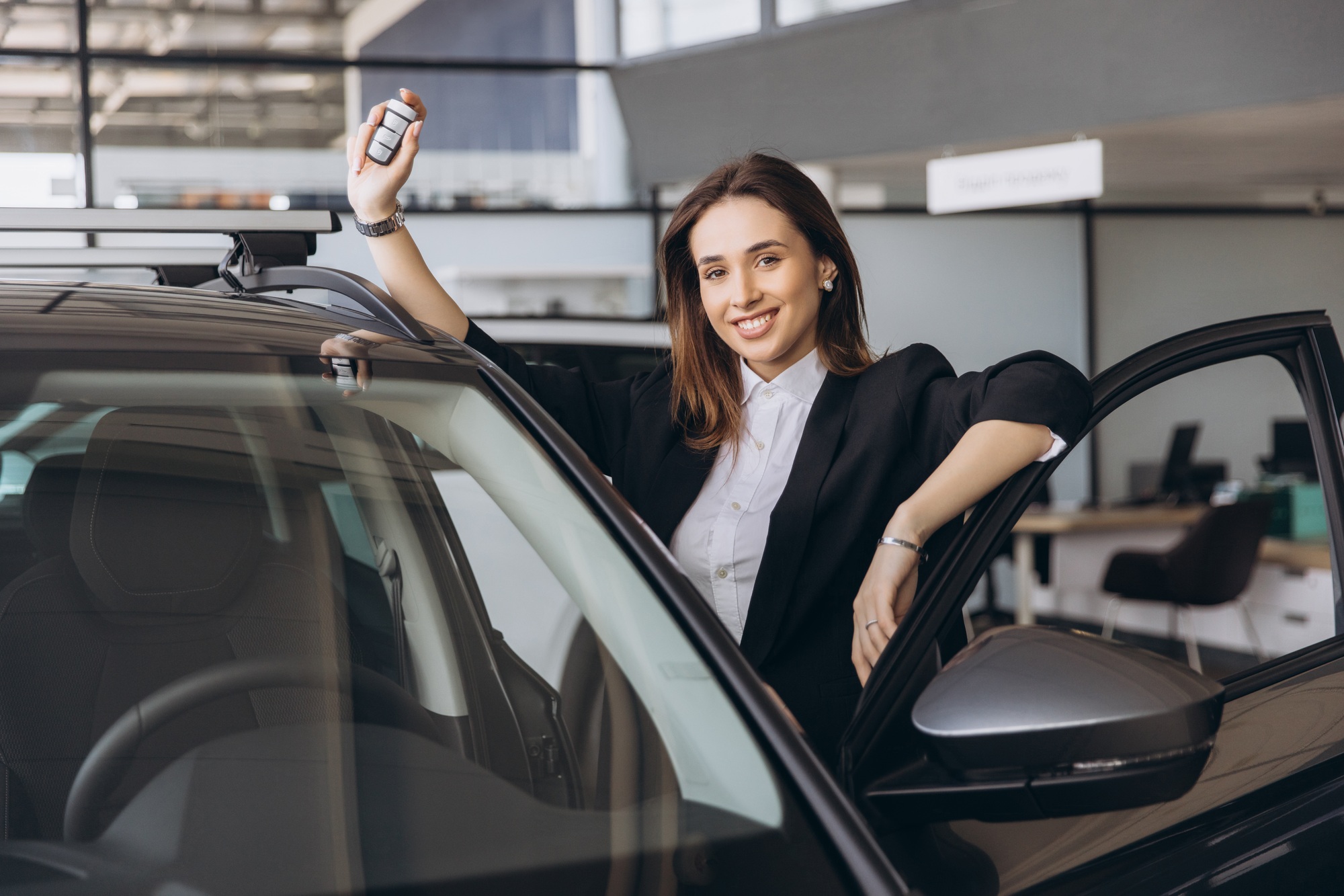 Saleswoman showing car keys in a car dealership