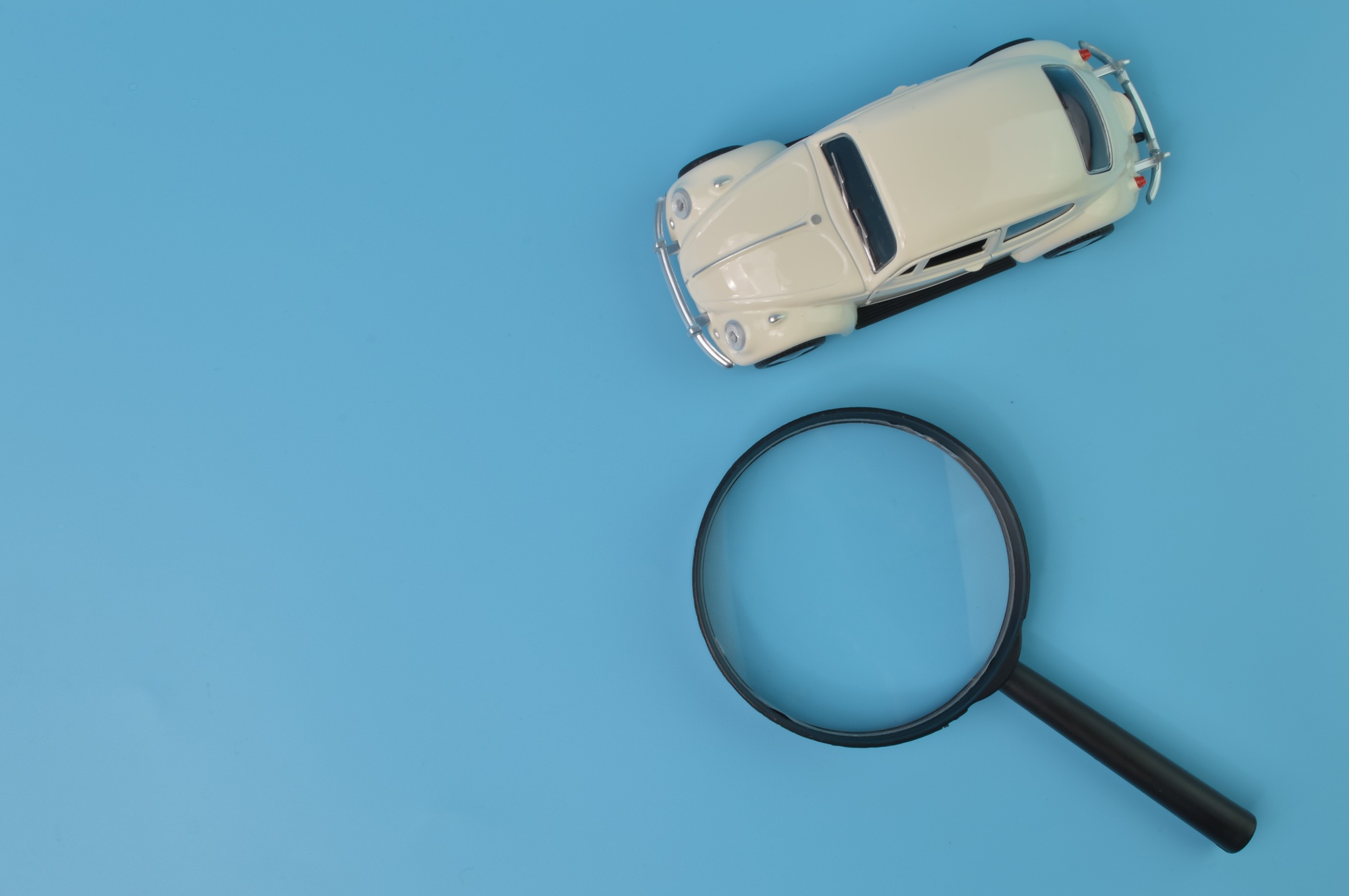 White retro car model and magnifying glass. Find a car and car search concept.